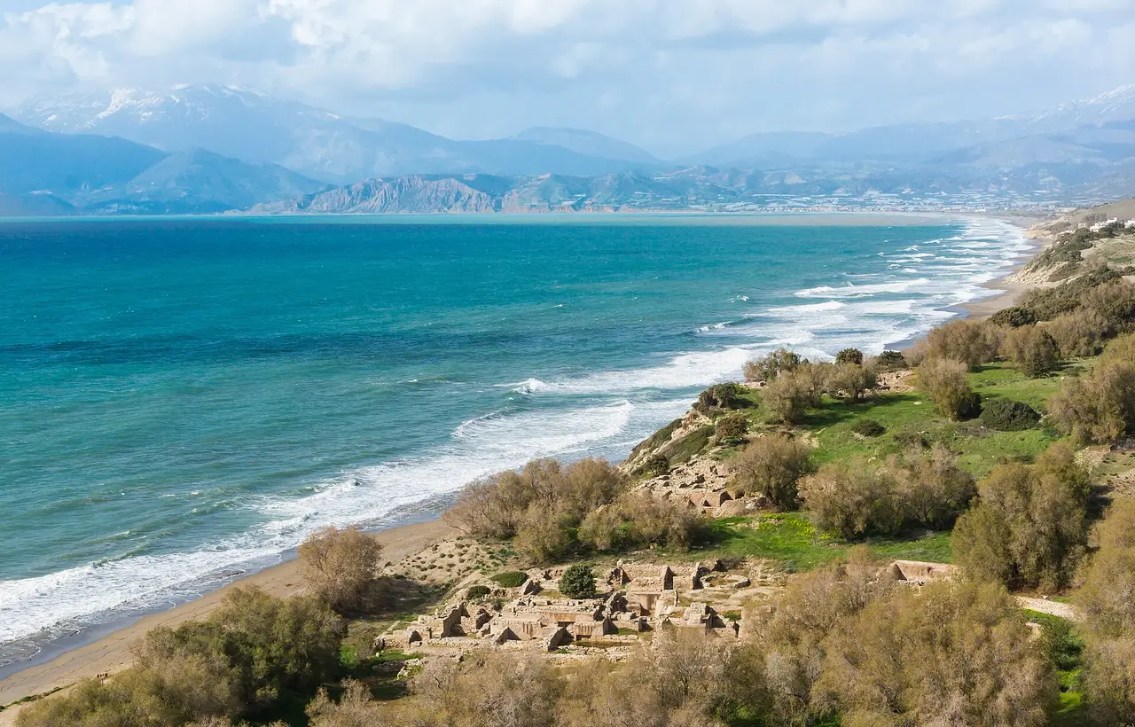 Turquoise sea and a long sandy bay below green hills on the south coast of Crete