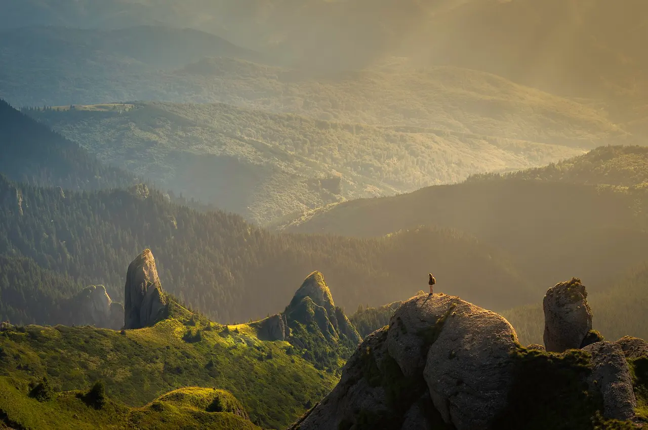 A walker on a rocky outcrop above misty mountain valleys at sunrise