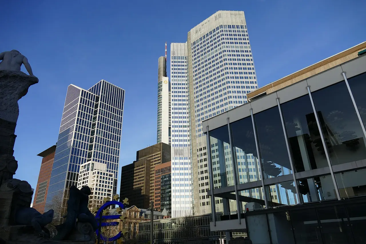 Tall glass office towers against a blue sky seen from below