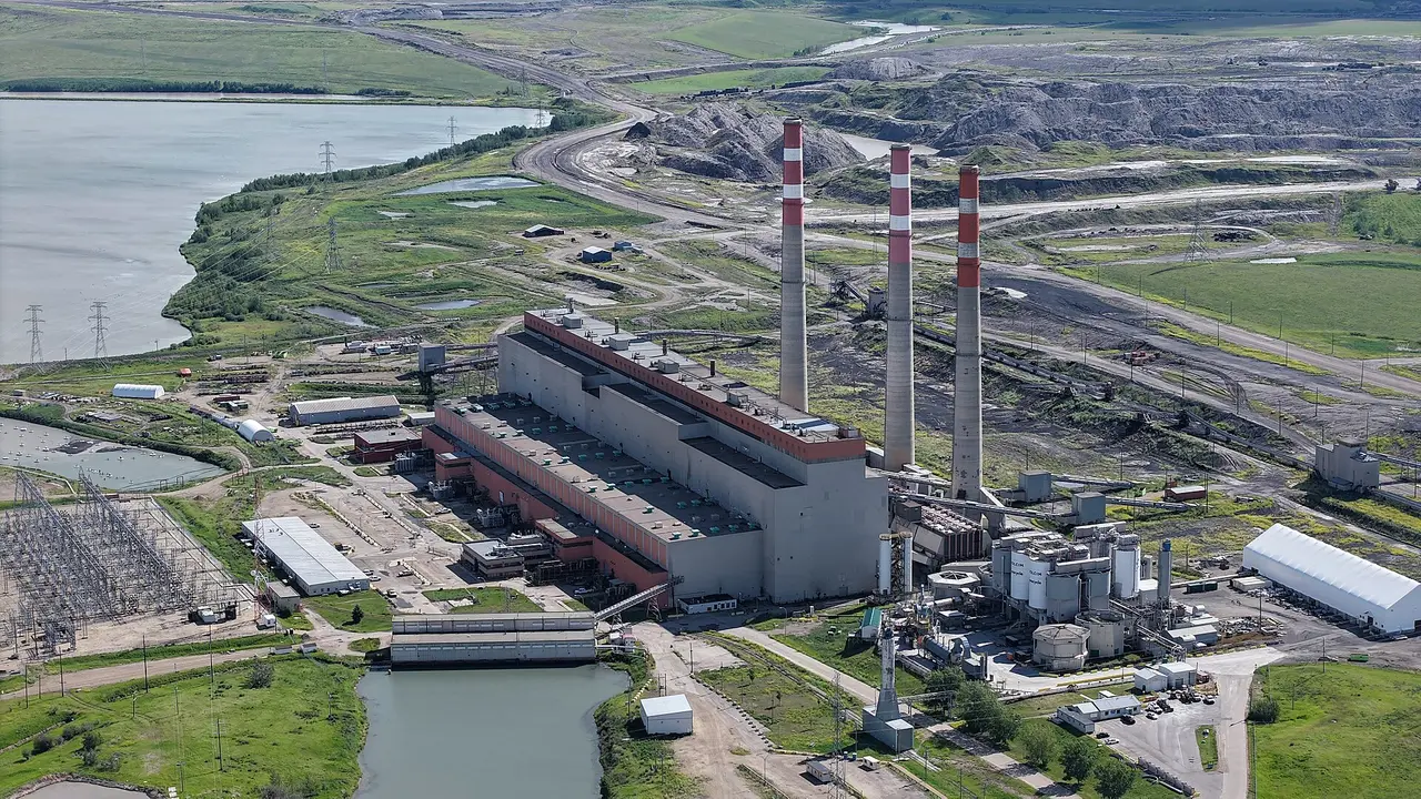 Aerial view of a power station with three chimneys beside a lake