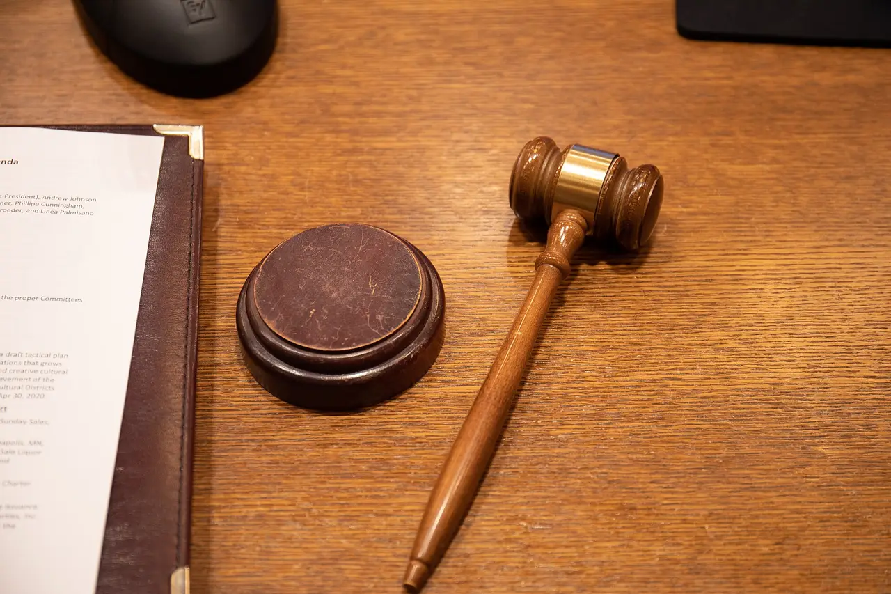 A wooden gavel beside its sound block on a desk