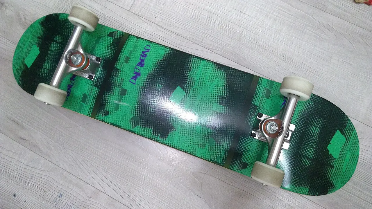 Green skateboard deck seen from below with trucks and wheels