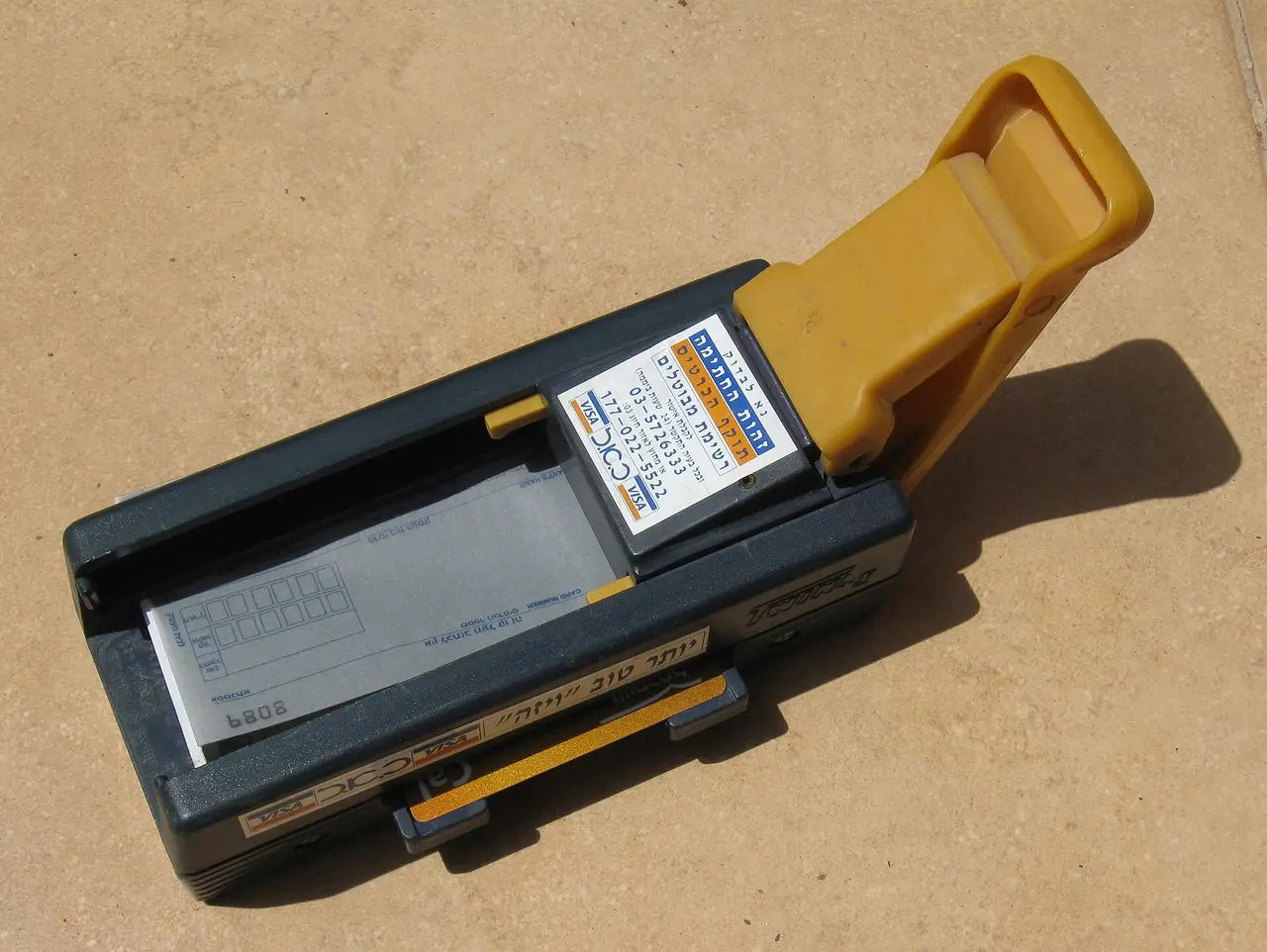 A manual credit card imprinter machine on a surface