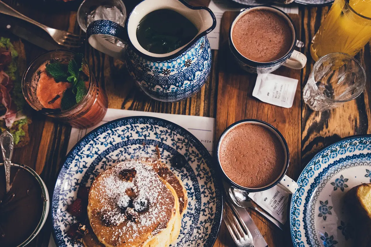 Plate of pancakes with cups of hot chocolate on a wooden table