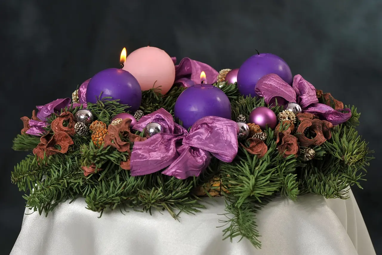 An Advent wreath with violet and pink candles and purple bows