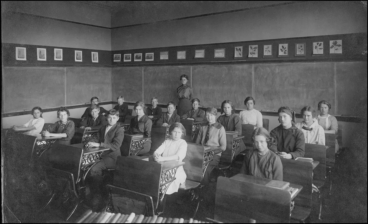 Black-and-white photo of pupils at desks in an early twentieth-century classroom