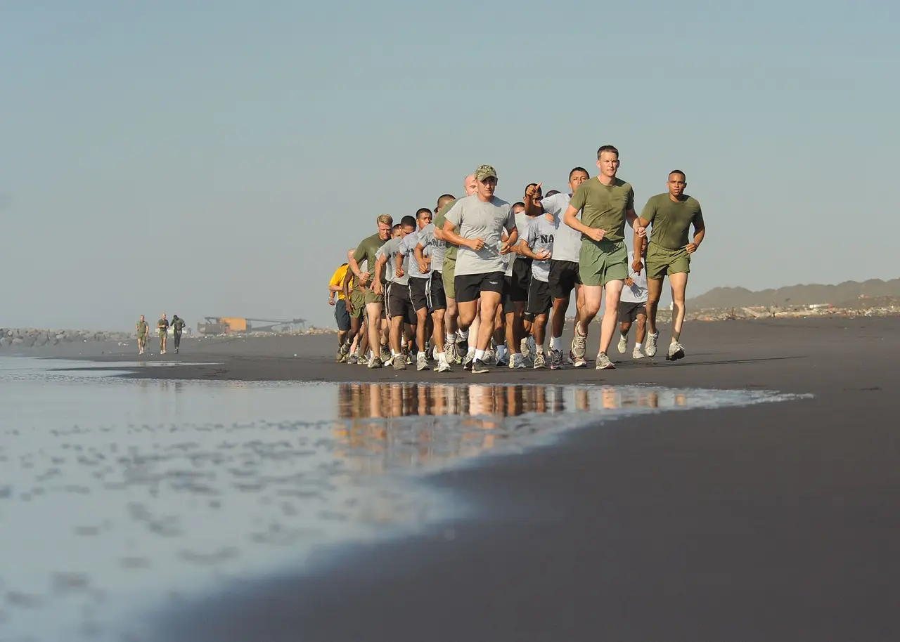 Line of runners in formation along a dark sand beach