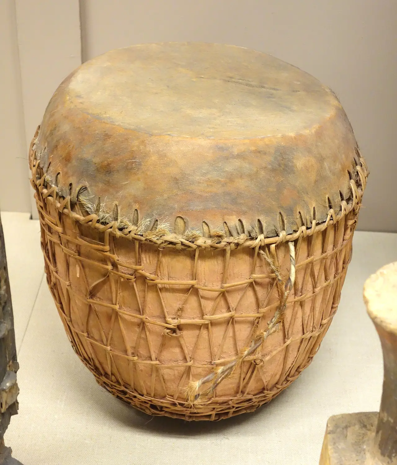 A round drum with a skin head and woven cord around its body