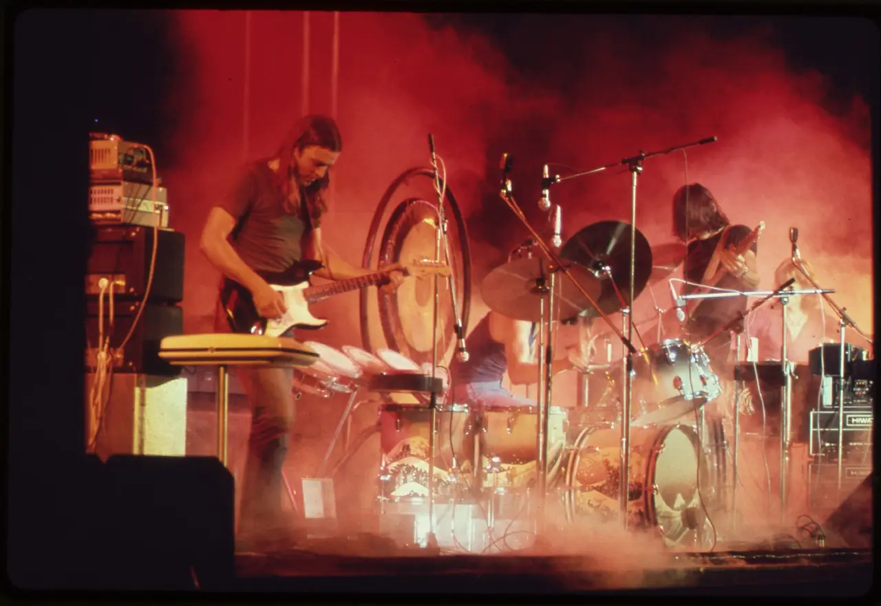 Rock band performing on a stage filled with red light and smoke