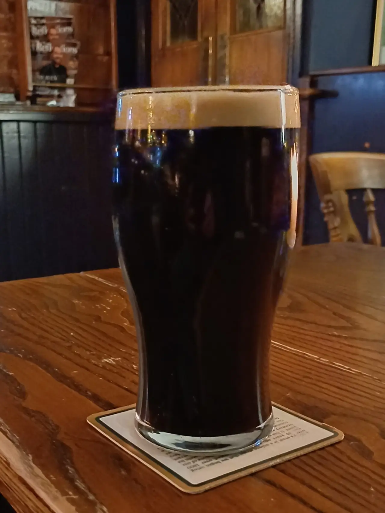 Dark pint of porter on a beer mat on a wooden table