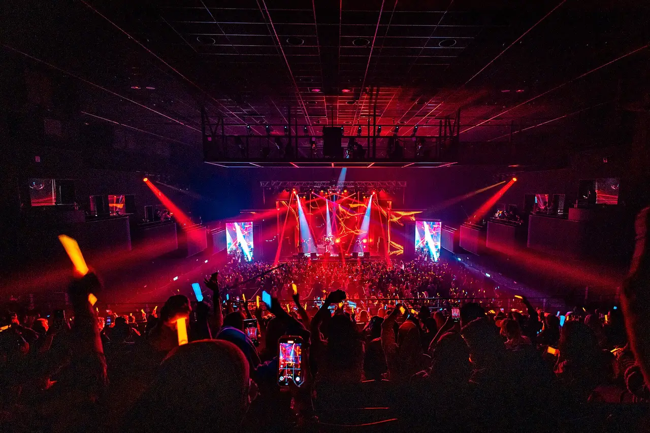 Large crowd in front of a lit stage at a night music festival