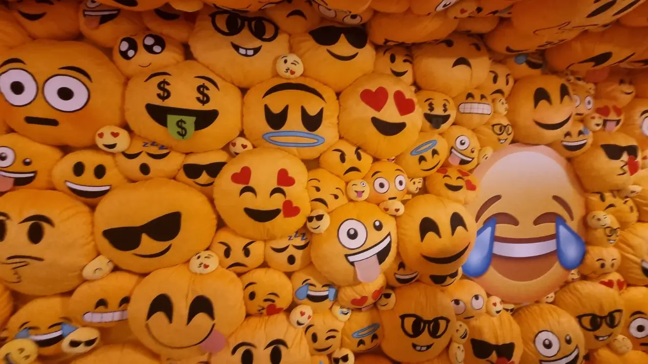 A heap of yellow emoji cushions showing many different faces
