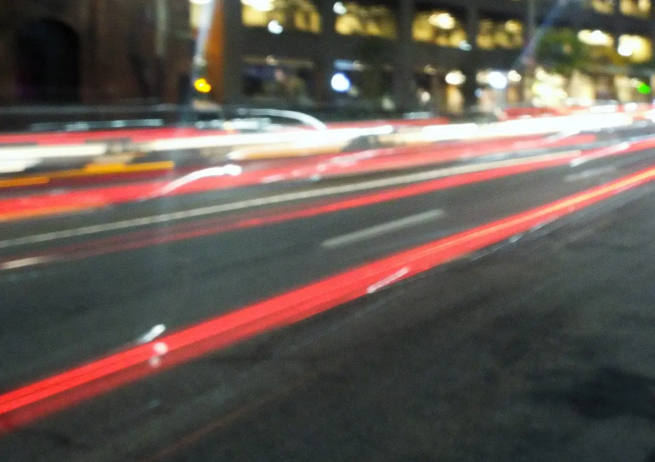Red and white light trails from cars on a dark city road