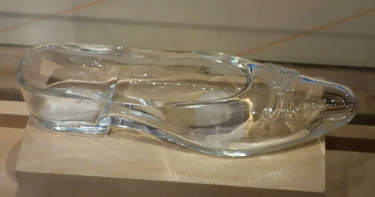 A clear glass shoe on a wooden display stand
