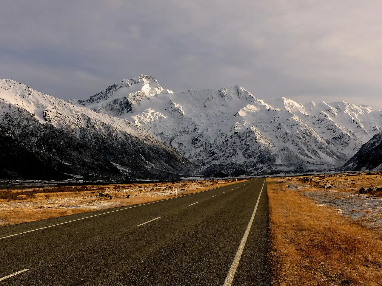 Straight road leading to snowy mountains in New Zealand