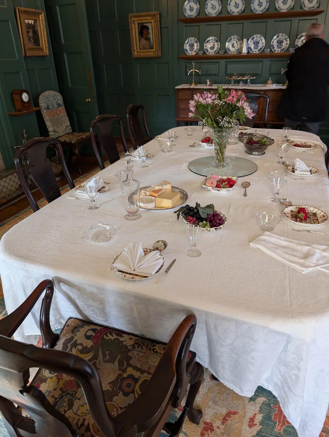 A dining table with a white cloth, plates and flowers in a panelled room