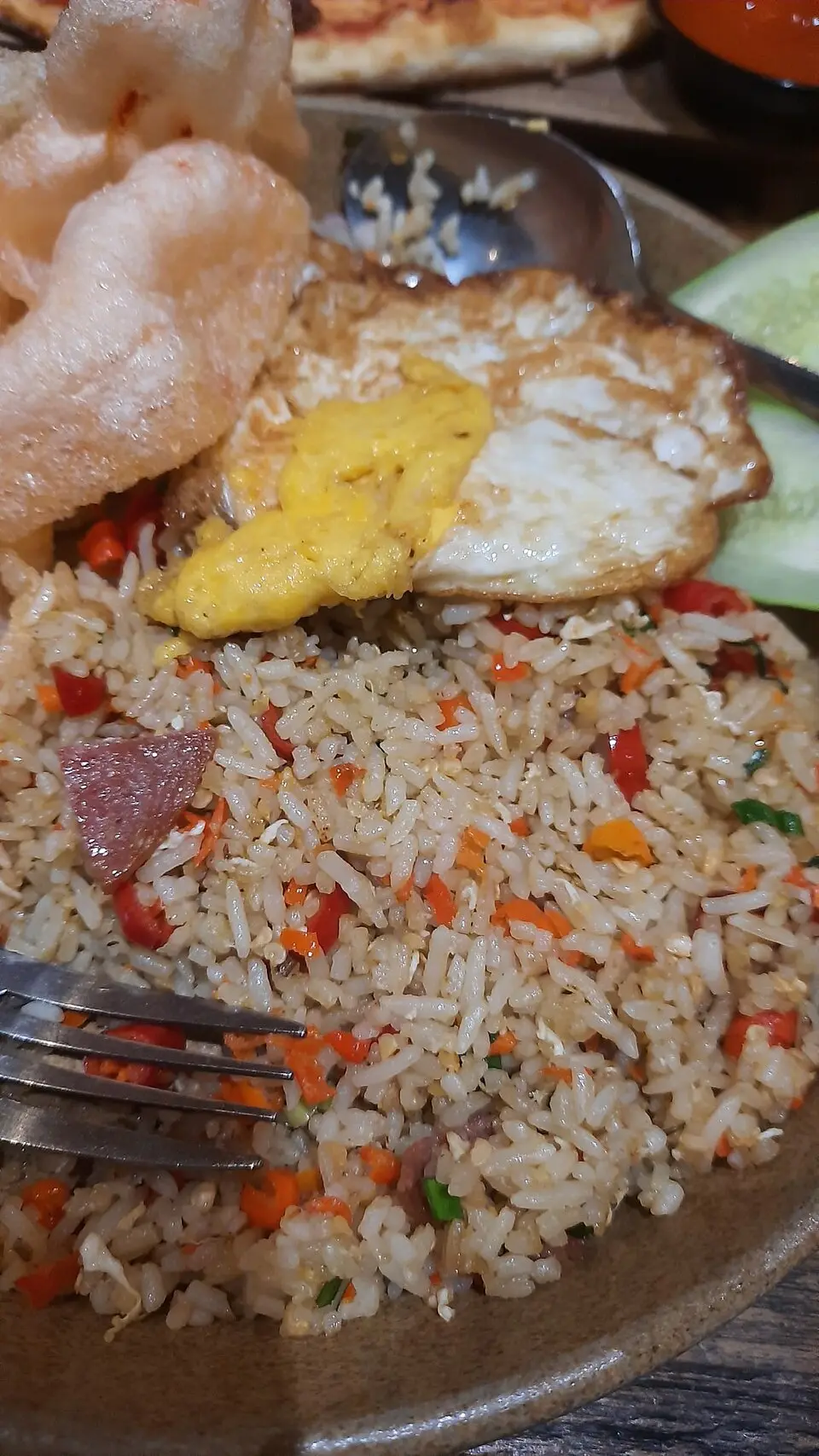 A plate of fried rice with vegetables and a fried egg