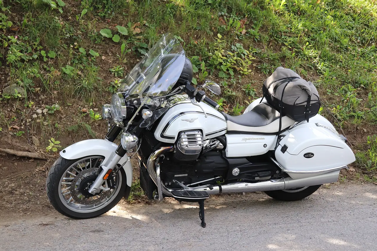 A white Moto Guzzi touring motorcycle with panniers parked at the roadside