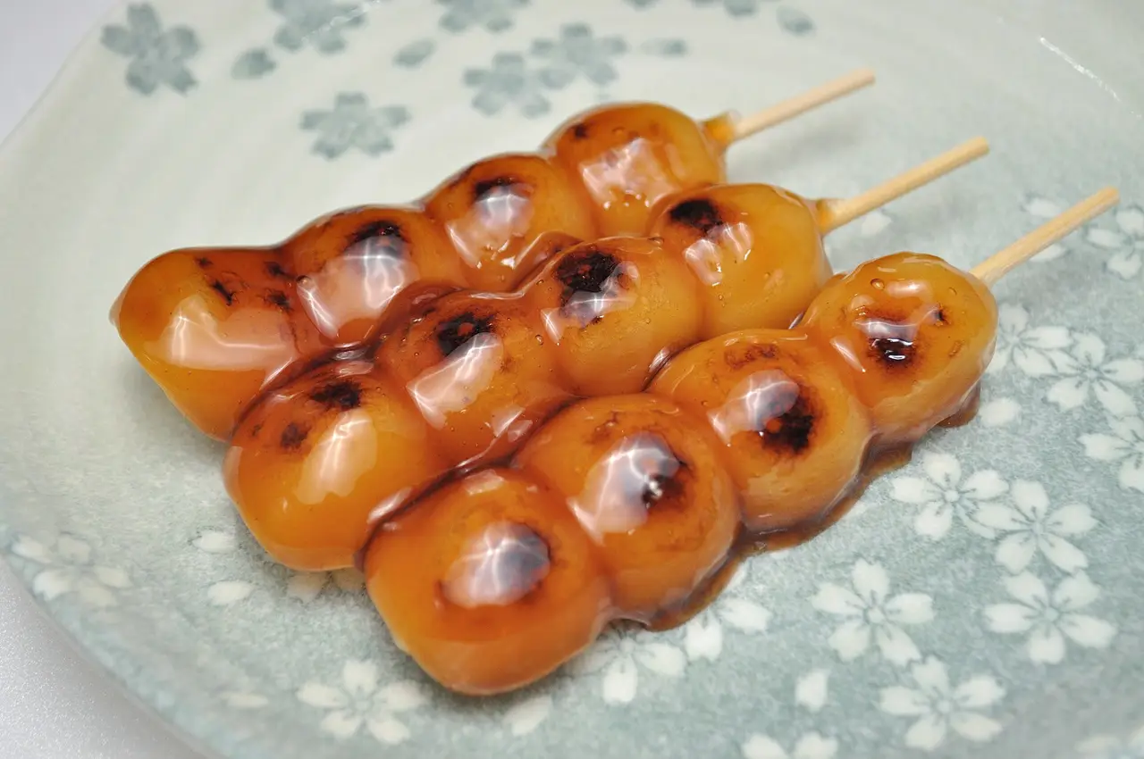 Skewered rice dumplings with a glossy glaze on a blossom plate