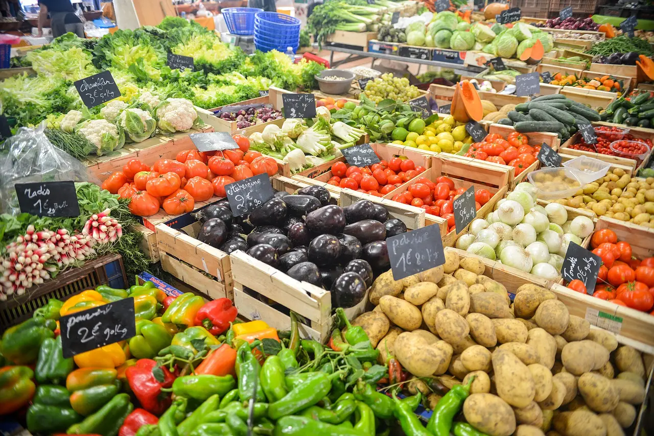 A market stall stacked with peppers, tomatoes, aubergines and potatoes