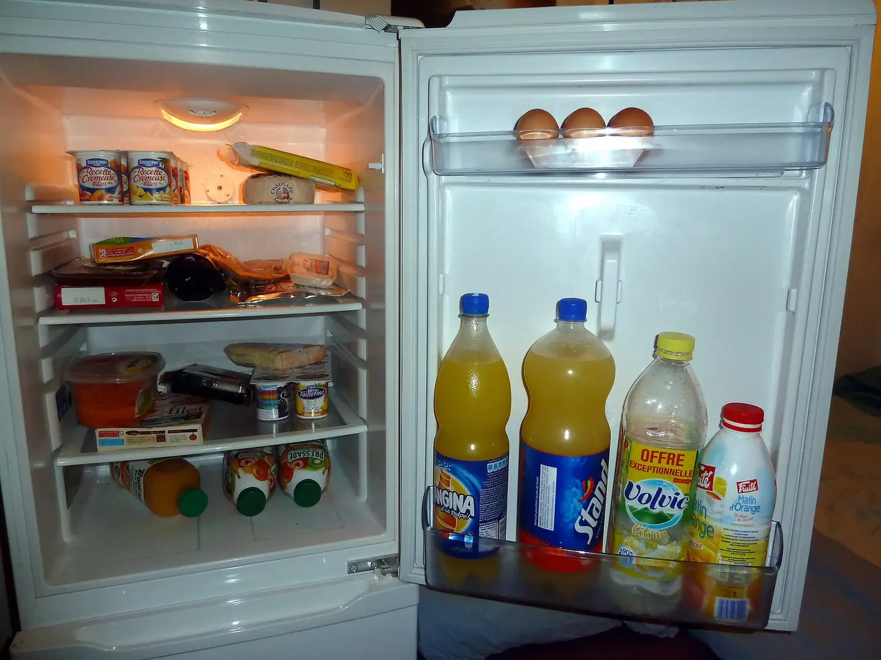 An open fridge with bottled drinks, eggs and food on the shelves