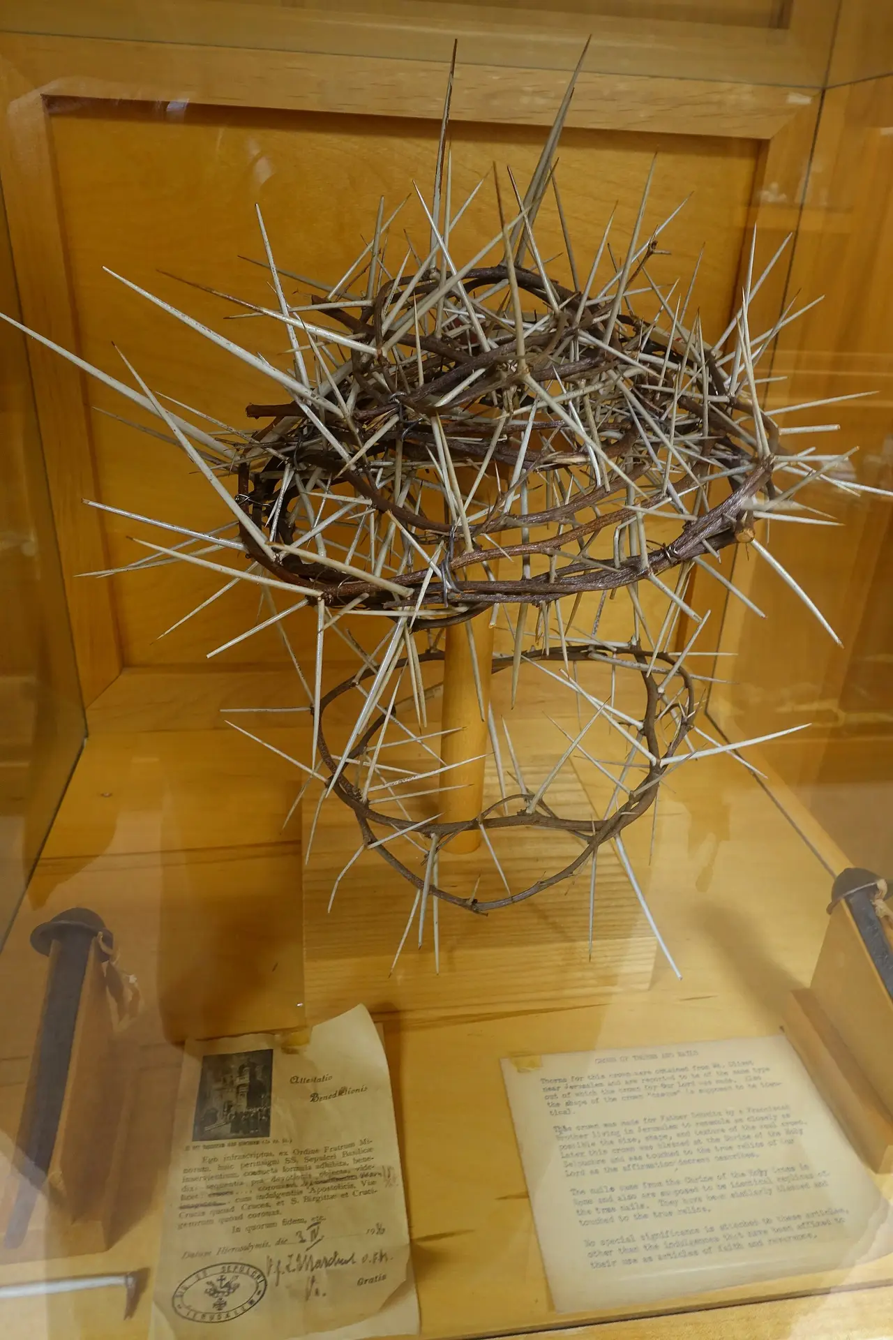 A crown of thorns in a glass museum case with nails and a card