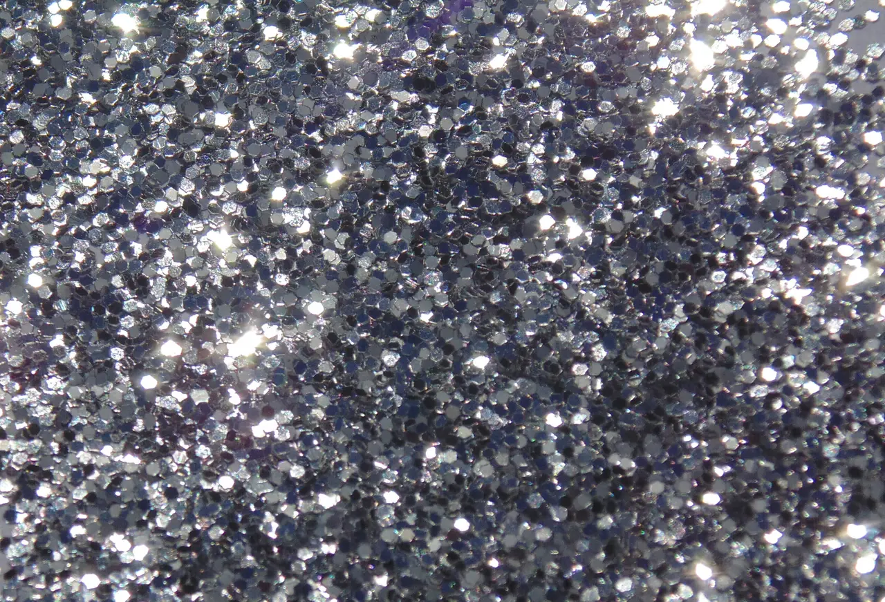 A dense layer of silver glitter flakes sparkling in the light