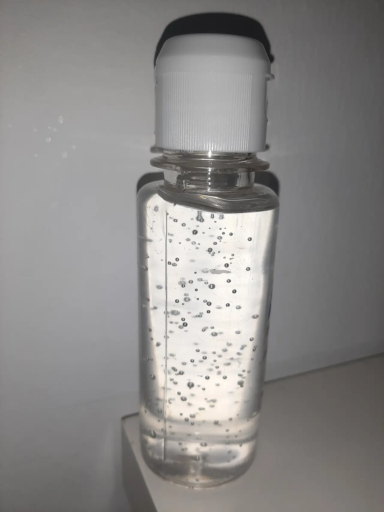 A clear bottle of hand sanitizer gel with a white cap