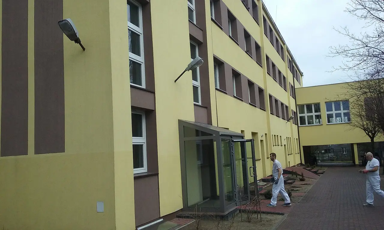 A pale yellow multi-storey care home building with a paved path