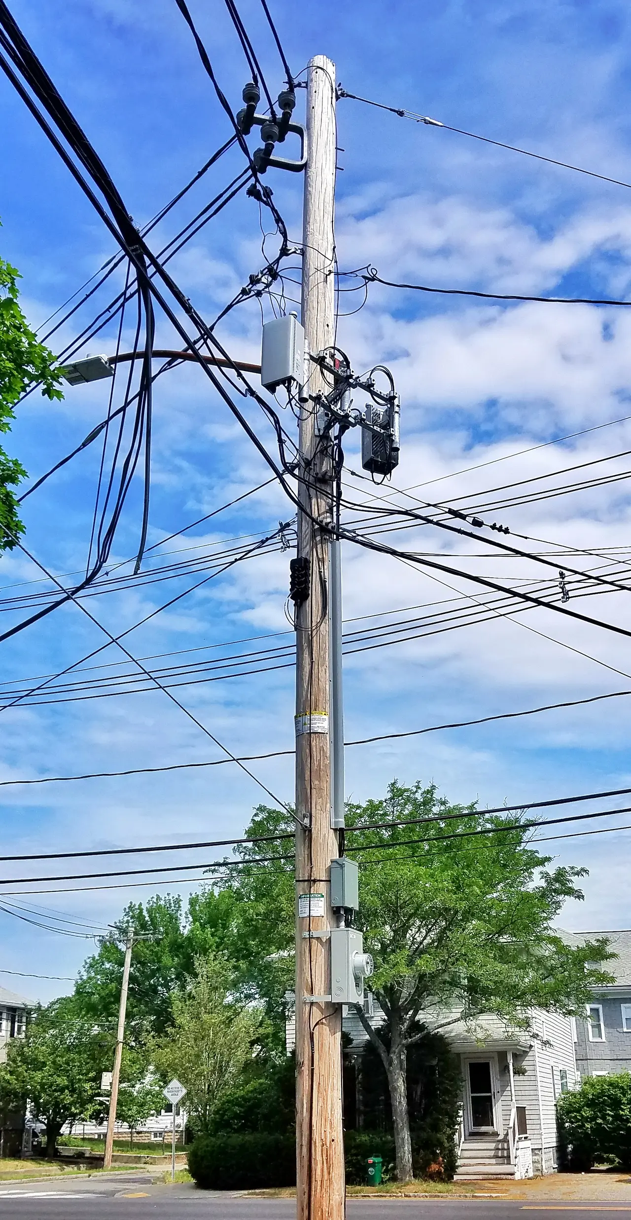 A tall utility pole with wires and 5G antennas against a blue sky