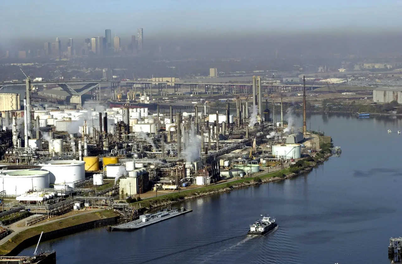 Aerial view of a river channel lined with industrial plants and a distant city