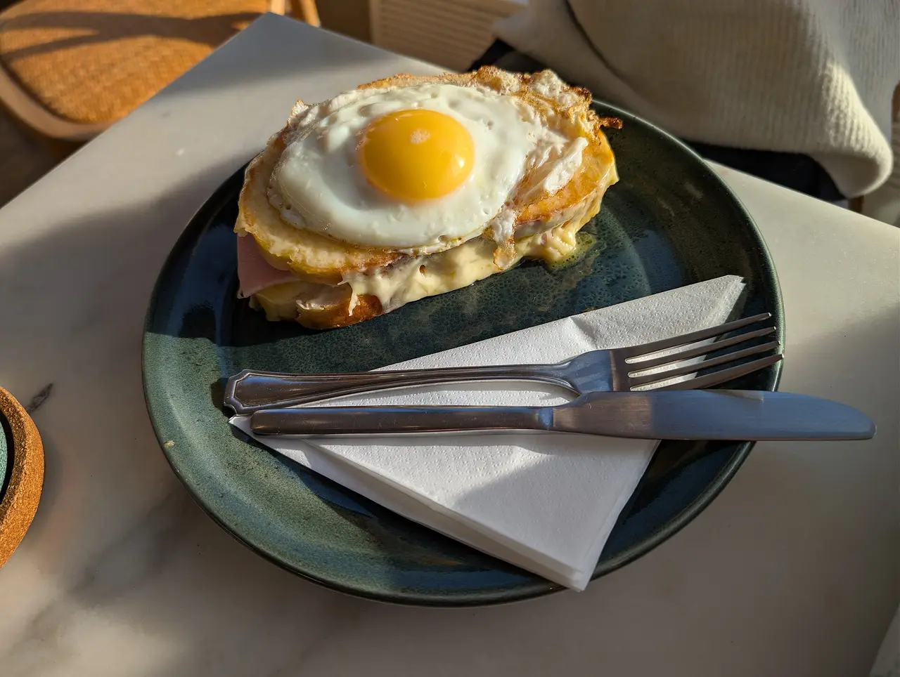A toasted sandwich topped with a fried egg on a dark plate