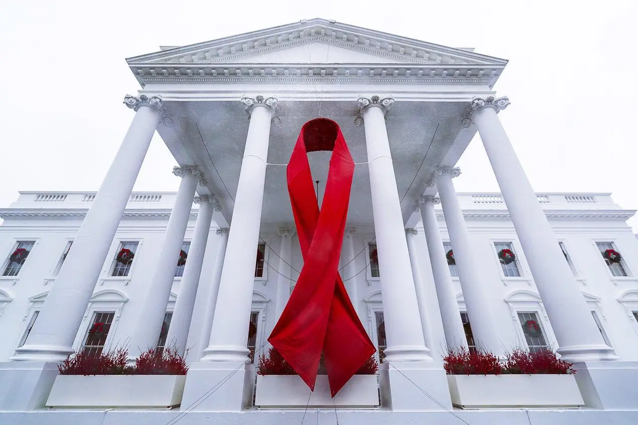A large red ribbon hanging between white columns of the White House