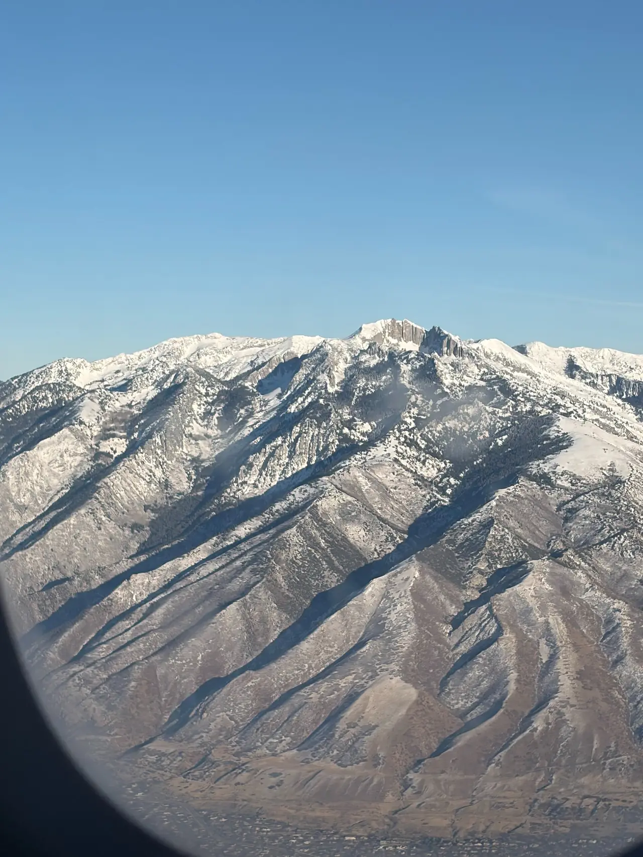 Snowy mountain ridges seen through the curved edge of an aeroplane window