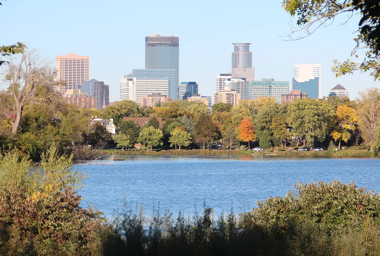 Minneapolis skyscrapers behind a blue lake and autumn trees