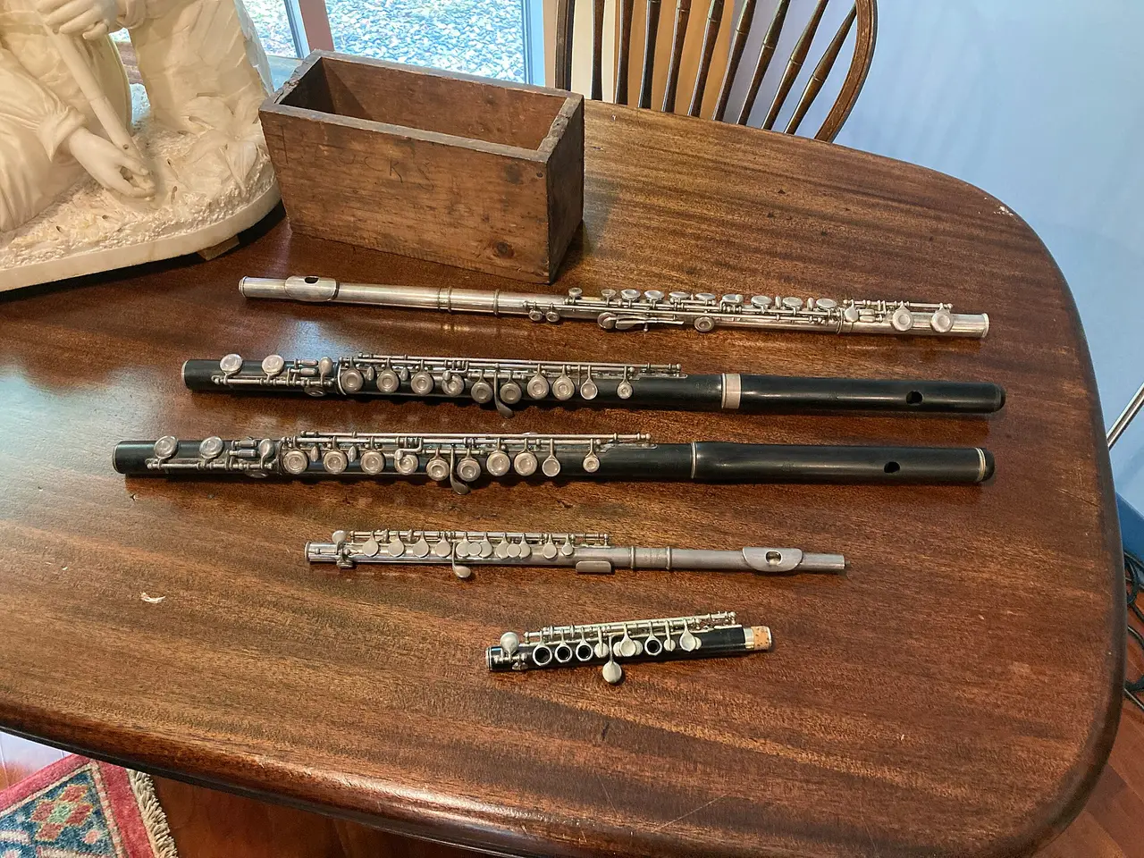 Five antique flutes laid in a row on a wooden table