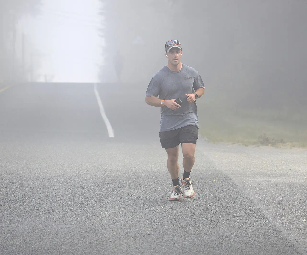 A runner on a foggy road between trees