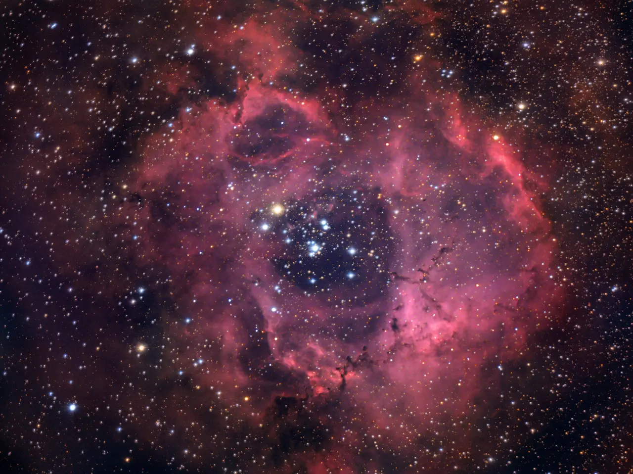 A red and pink ring-shaped nebula with stars at its centre