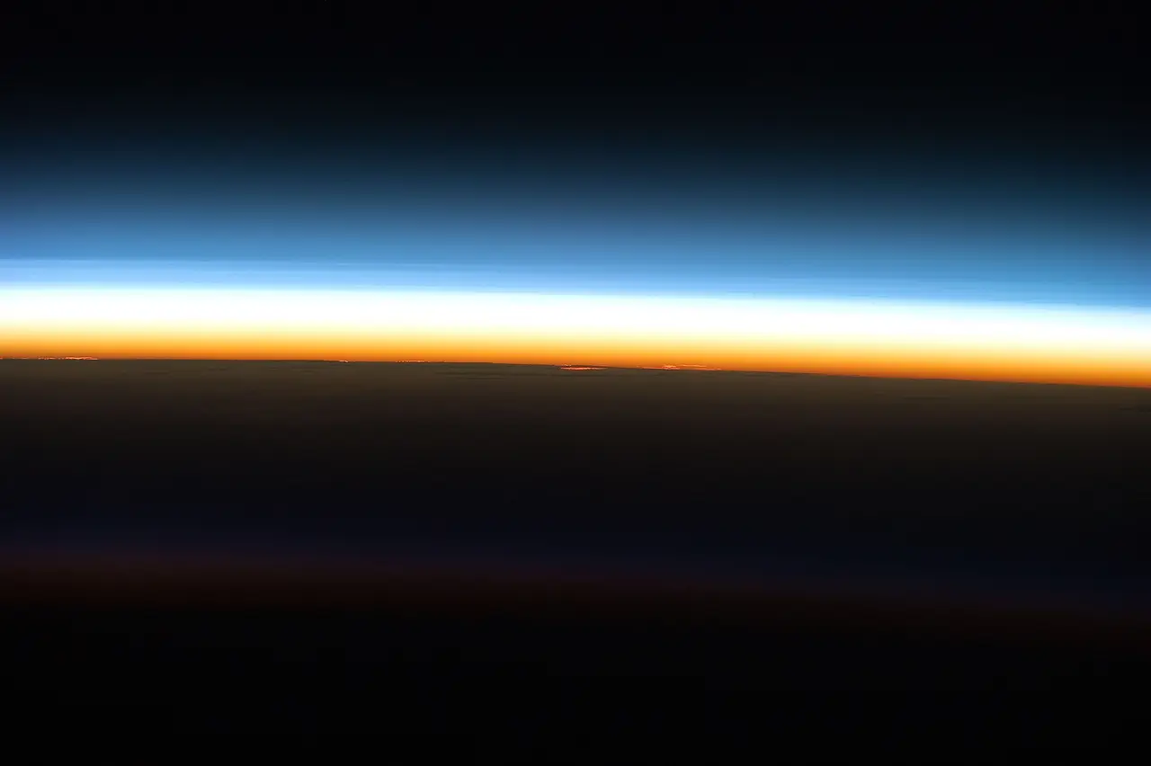 Thin blue, white and orange bands of atmosphere above the dark limb of Earth