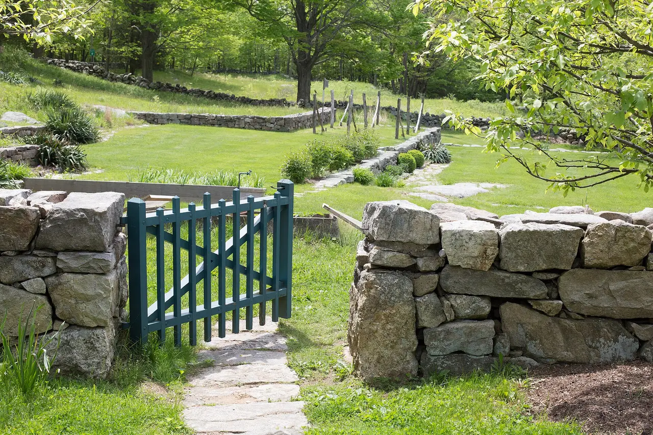 A green garden gate in a stone wall beside a path