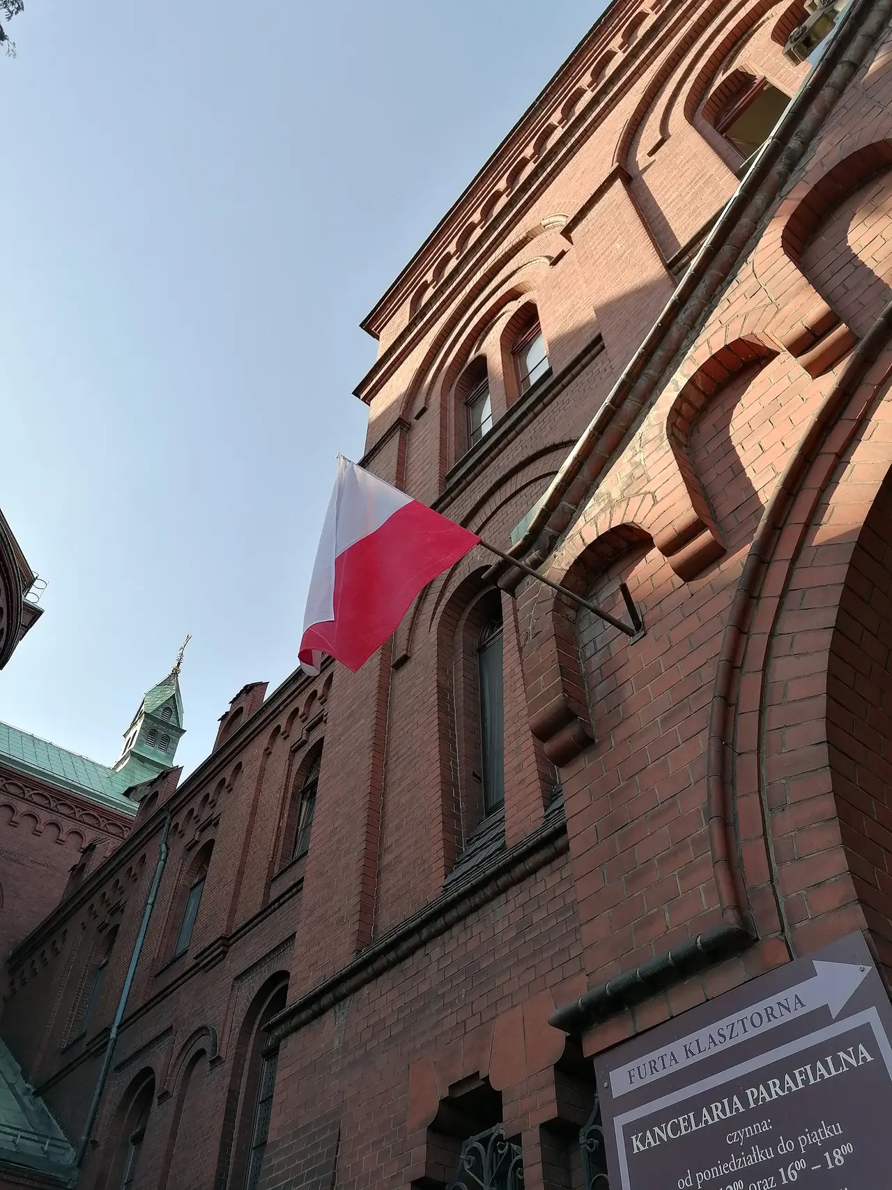 A white and red flag on the wall of a red brick church