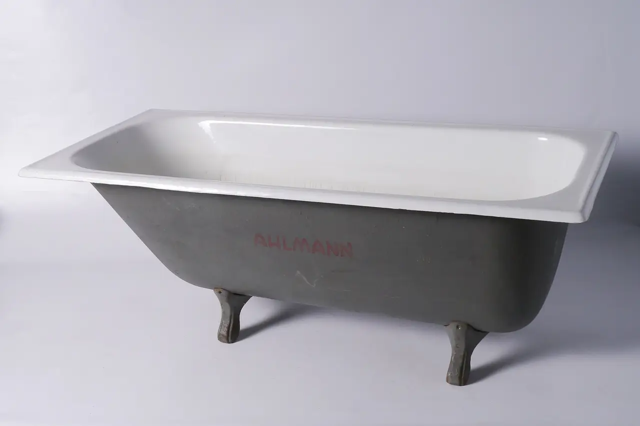 A white cast-iron bathtub on four feet against a grey background