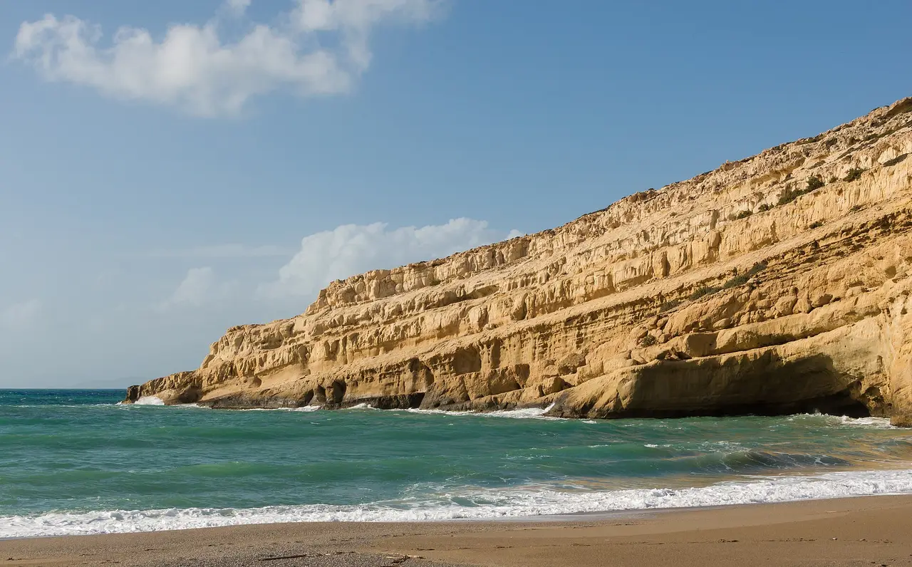 A pale sandstone cliff beside a beach and turquoise sea