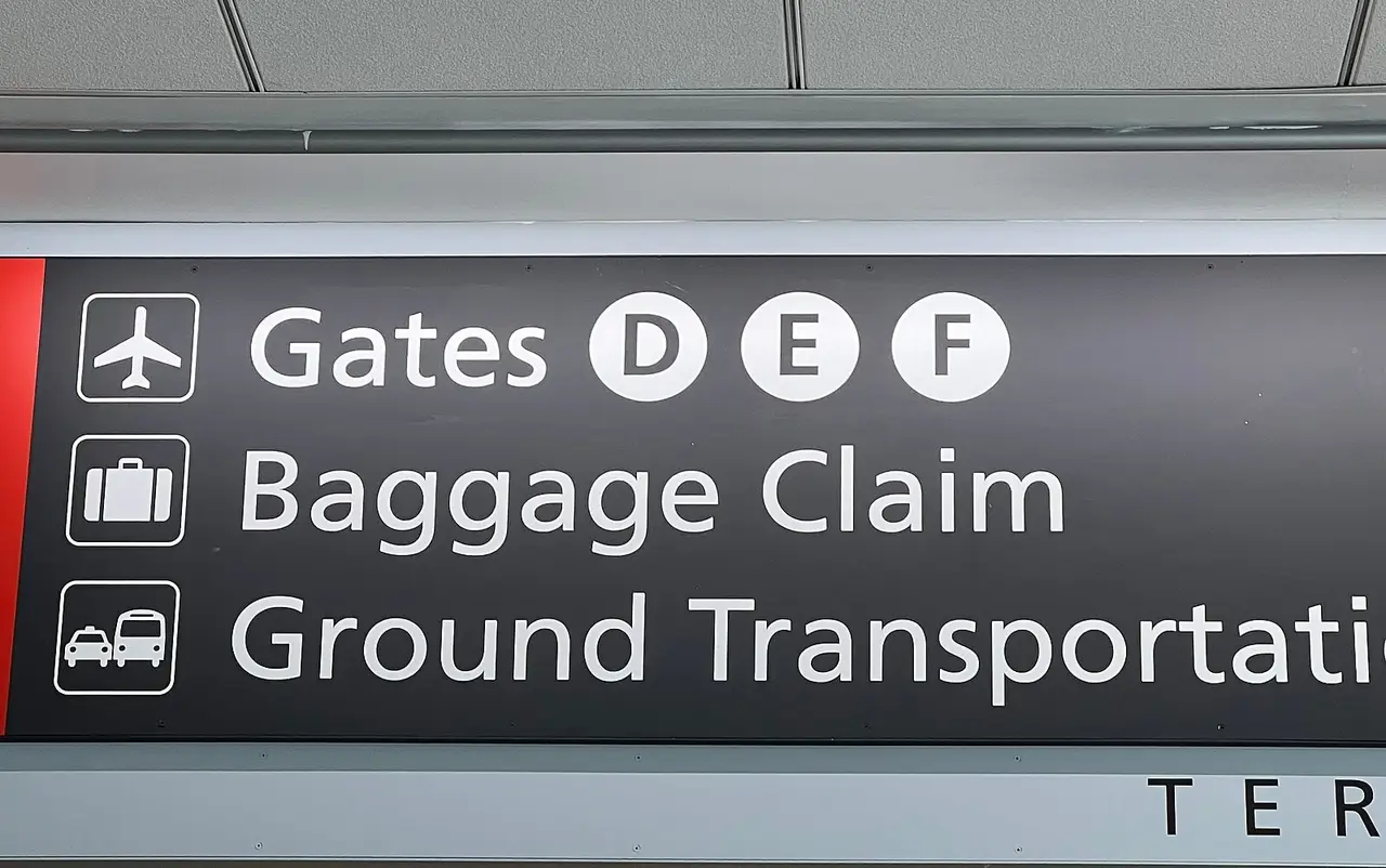 An airport sign pointing to gates, baggage claim and ground transportation