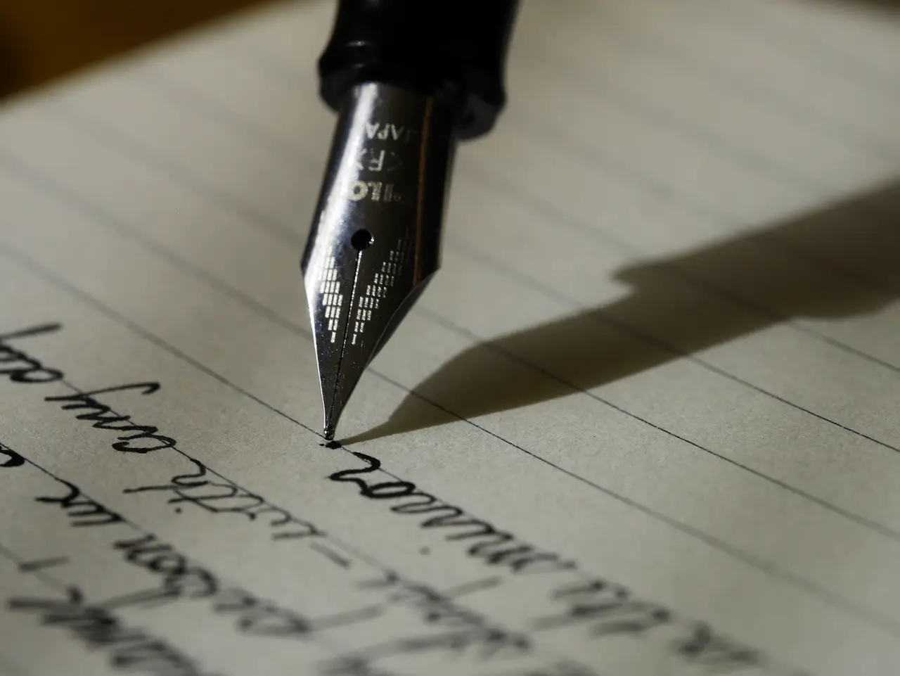 The nib of a fountain pen writing on lined paper