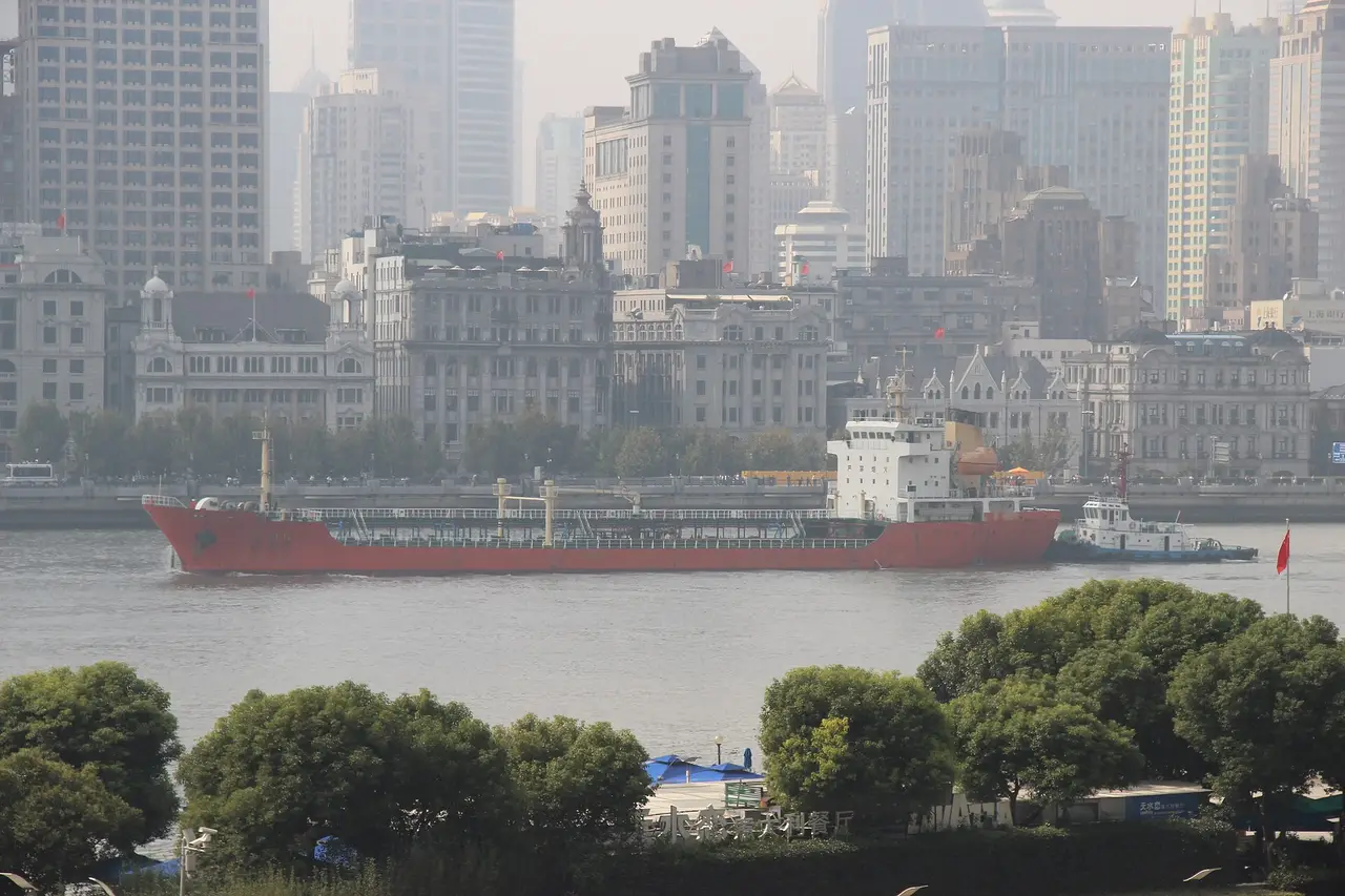 A red tanker on a river in front of Shanghai buildings