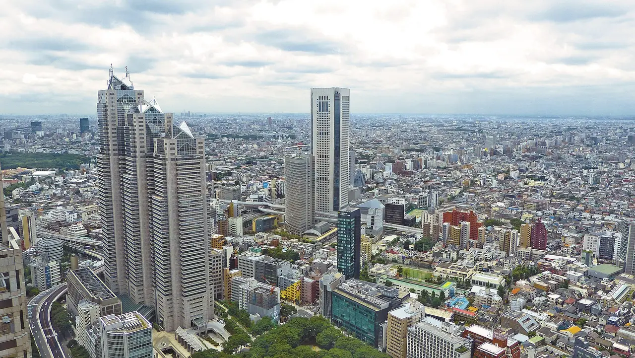 Tokyo's skyscrapers rising above dense city streets under a cloudy sky