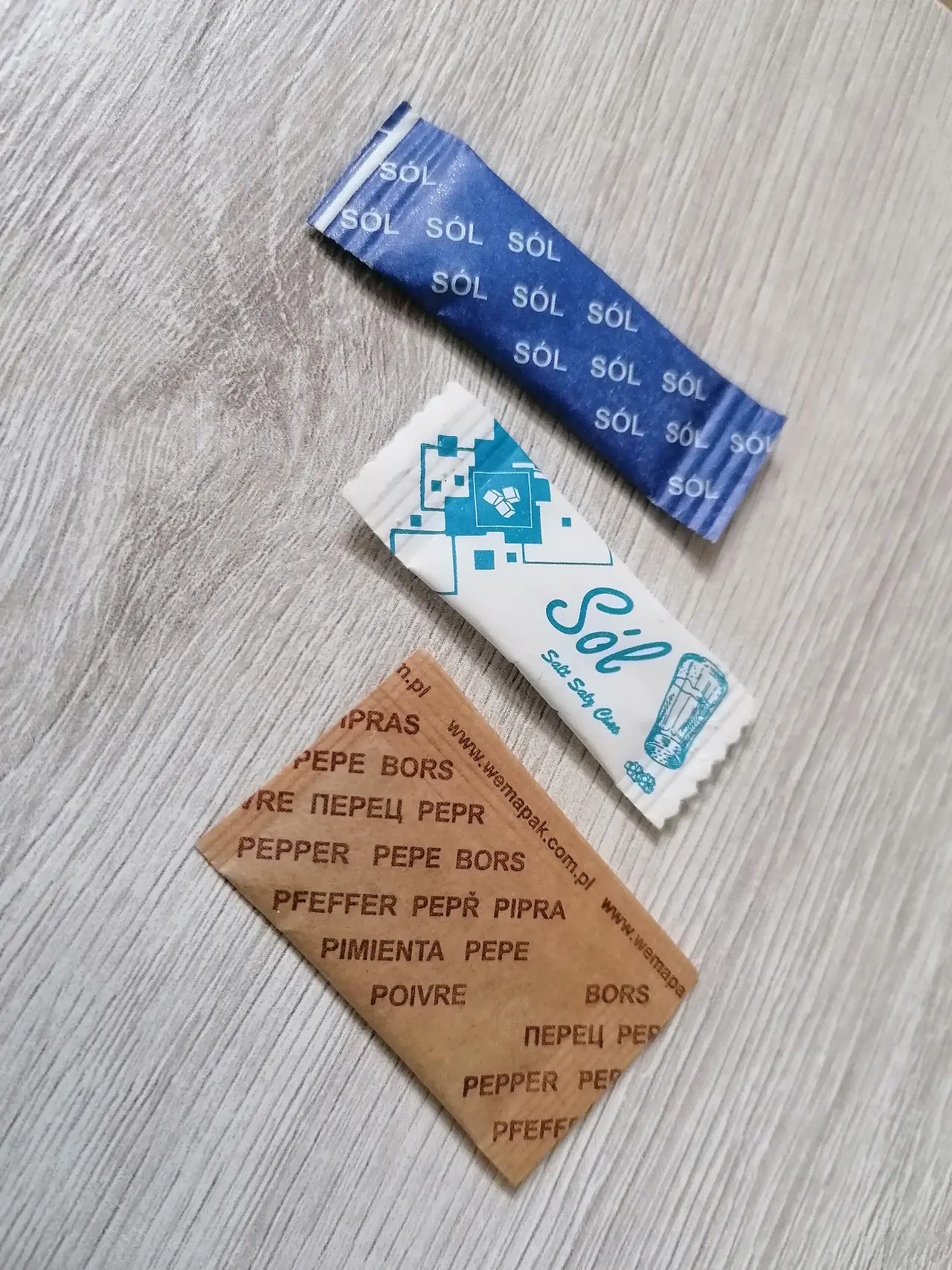 Small paper sachets of salt and pepper on a table