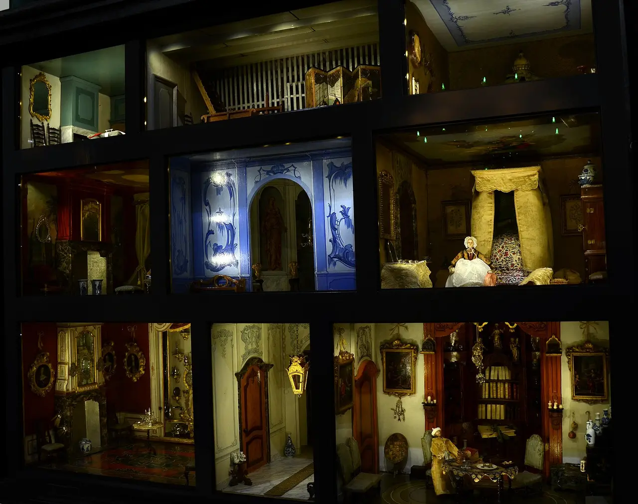 A dark cabinet dollhouse with many small furnished rooms