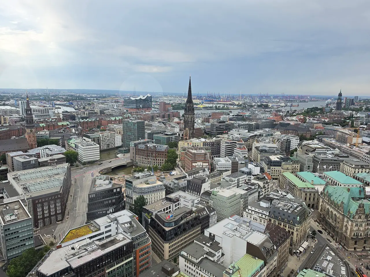 Rooftops and a church spire across Hamburg under a cloudy sky